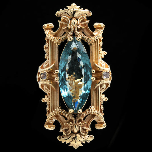 Decorative gold ring with baroque details abd a marquise cut with an aquamarine and pink diamonds a blue gemstone on a black backgroun