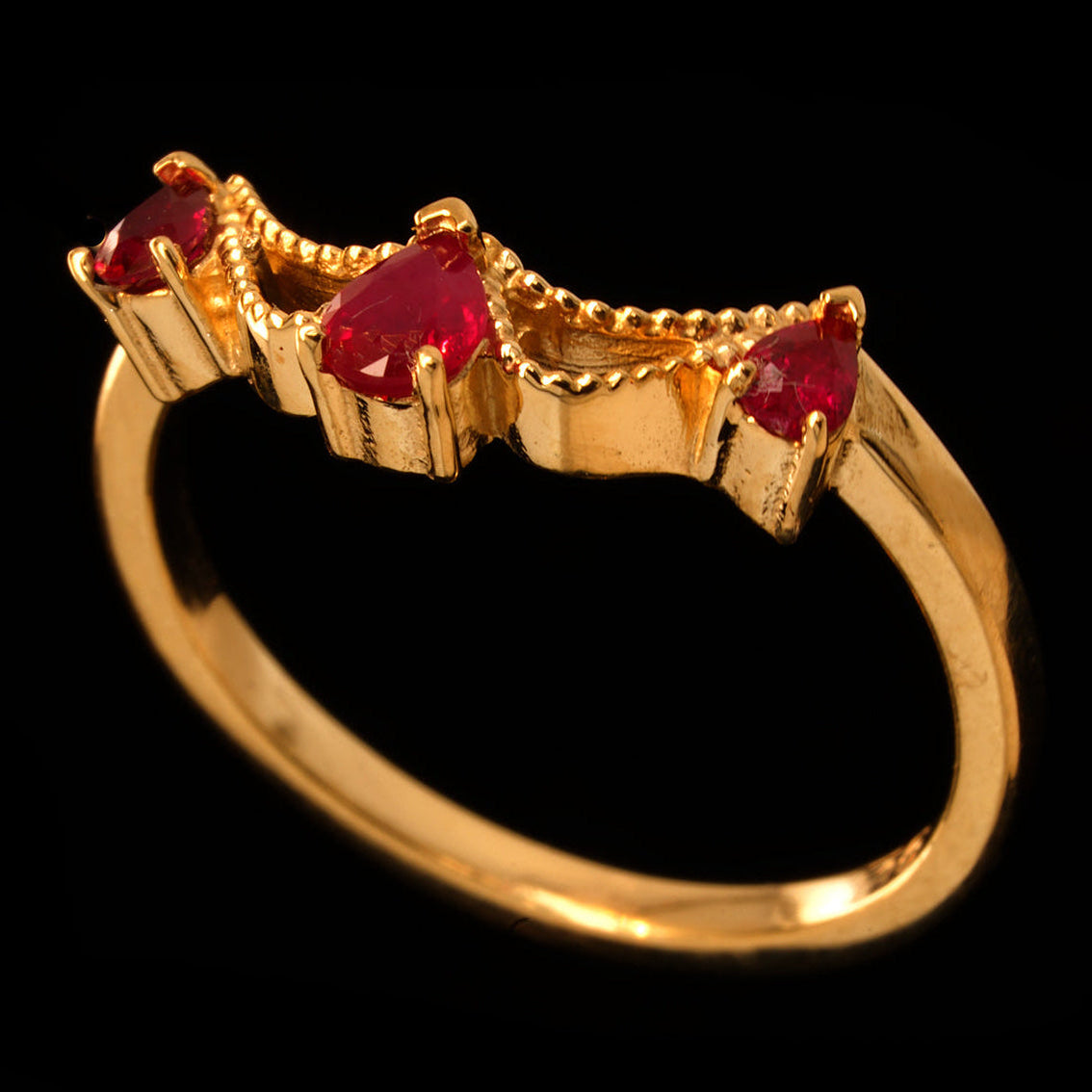 A handcrafted 9ct yellow gold engagement ring featuring three pear shaped rubies set in a wave-like design.