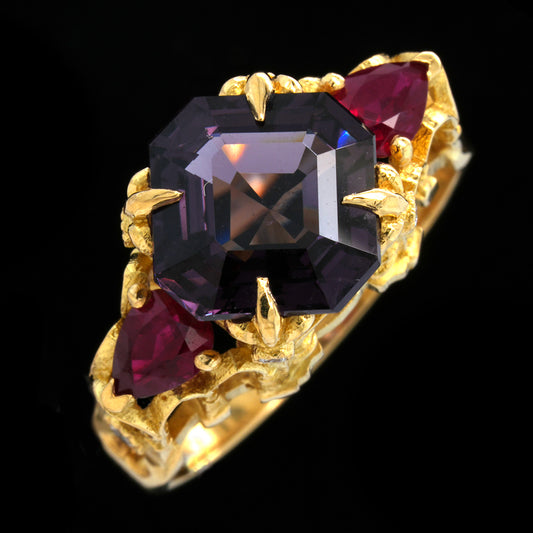 Gold ring with a plum coloured spinel, rubies and diamonds on a black background