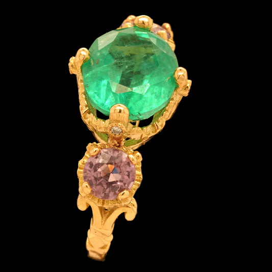 Gold pendant with an emerald and purple spinels on a black background