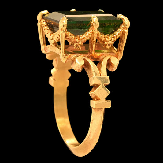 Gold ring with a green tourmaline gemstone on a black background