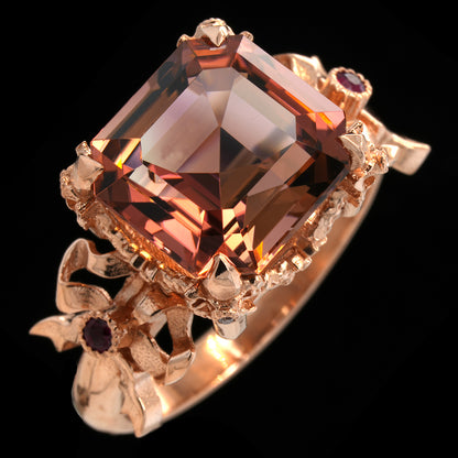 Gold ring with a large pink peach tourmaline gemstone on a black background