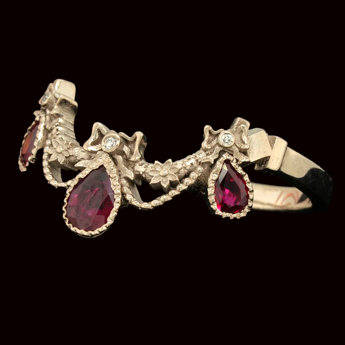 White gold engagement ring with rubies and diamonds on a black background