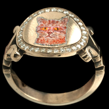 Gold ring with a cat face design and diamond accents on a black background