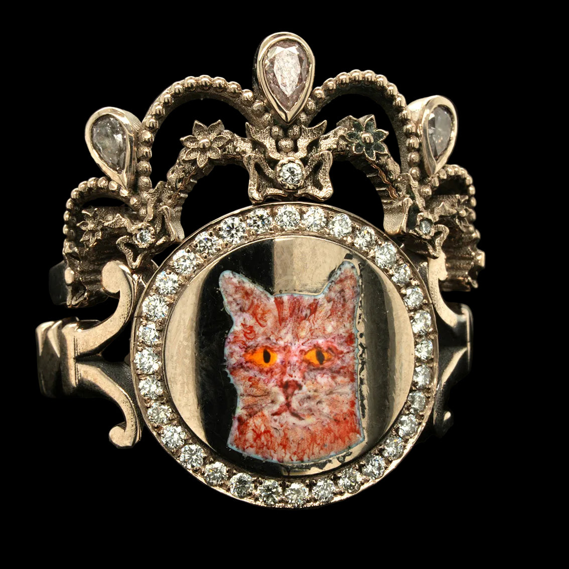 Decorative ring with a cat face inset and ornate design on a black background