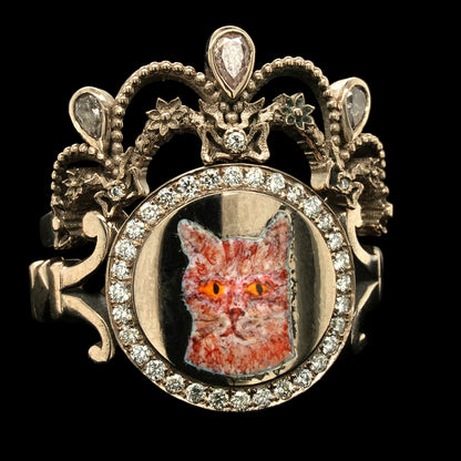 Decorative ring with a cat face inset and ornate design on a black background