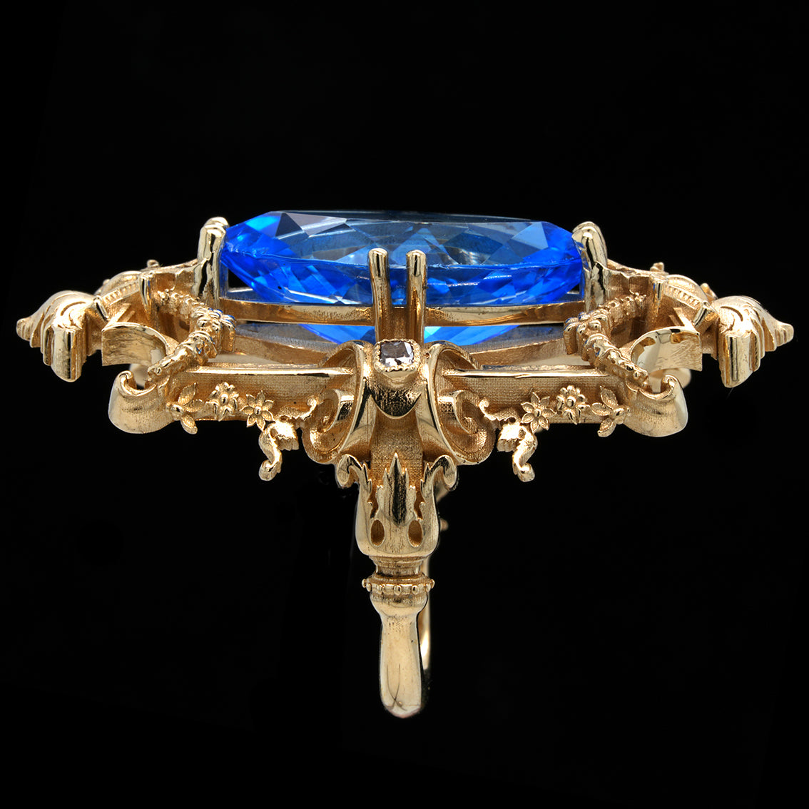 Gold ring with a swiss blue topaz on a black background