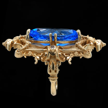 Gold ring with a swiss blue topaz on a black background