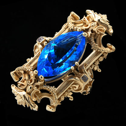Gold statement ring with a blue topaz on a black background