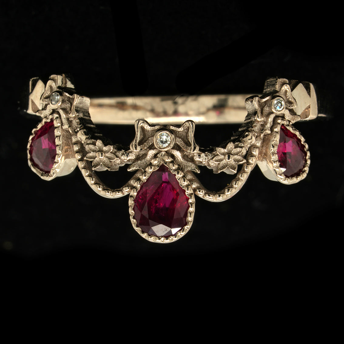 White gold engagement ring with rubies and diamonds on a black background