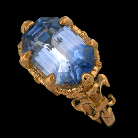 Gold ring with a large blue sapphire gemstone on a black background