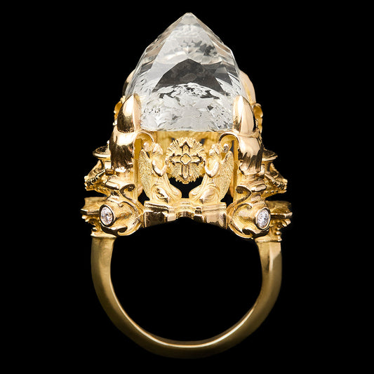 A gold ring featuring a large, faceted citrine gemstone and ornate gold detailing, shown against a solid black background.