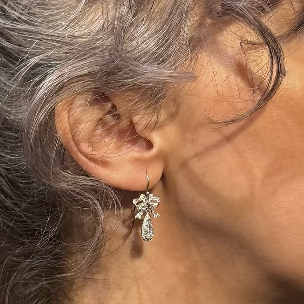 Close-up of an ear wearing a white gold and diamond earring with a blurred background