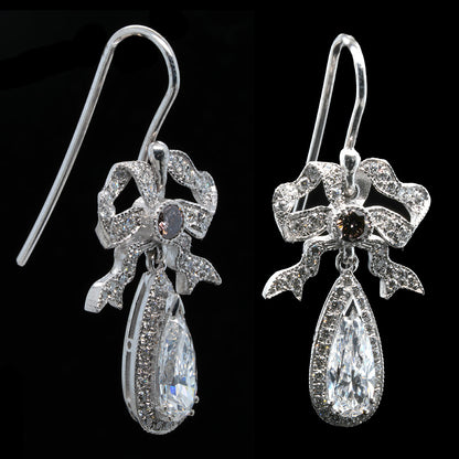 Pair of diamond earrings with bow design on a black background