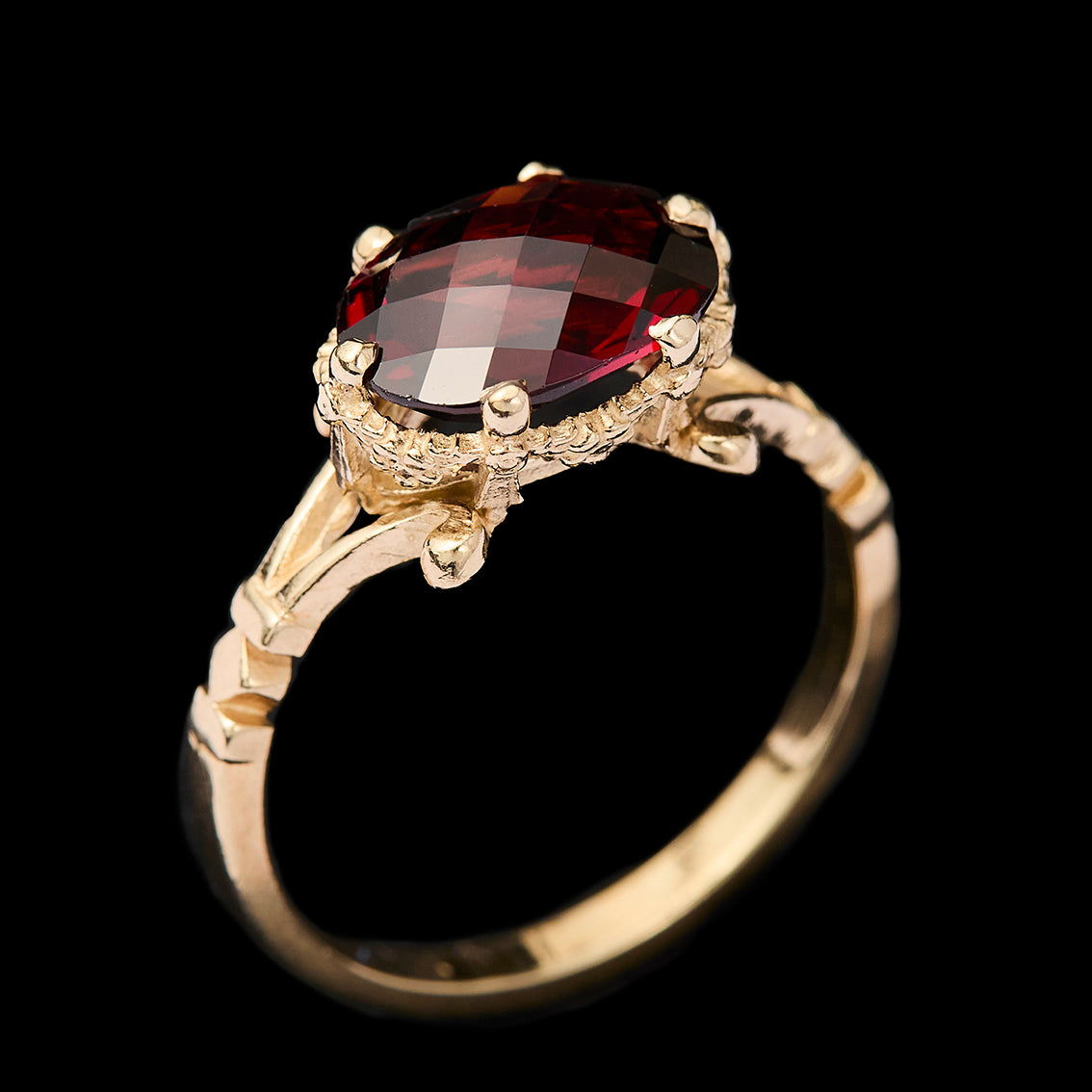 Gold ring with a garnet gemstone on a black background