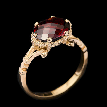 Gold ring with a garnet gemstone on a black background