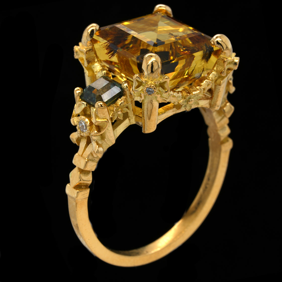 A yellow gold ring featuring a large heliodor gemstone, a smaller teal saphires, and tiny accent diamonds on a black background.