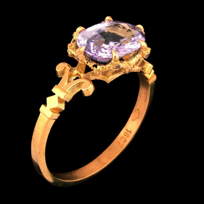 Gold ring with a lilac sapphire gemstone on a black background