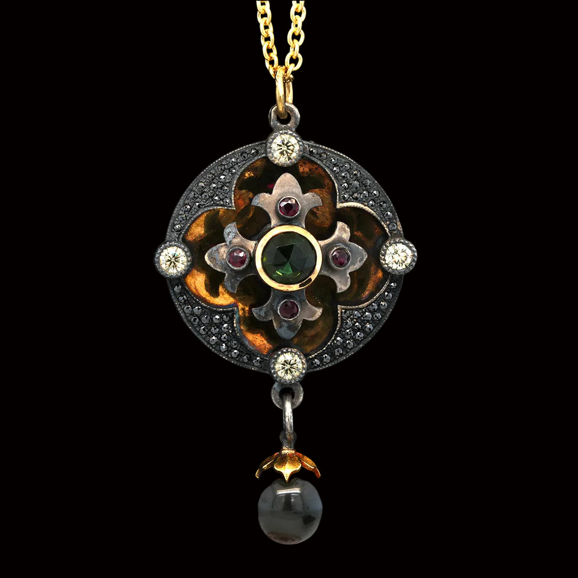 An ornate medieval-style pendant necklace featuring a gold chain, a circular blackened silver disk with gold back, ruby, diamond and black diamond accents, and a dangling dark pearl, displayed on a black velvet background.