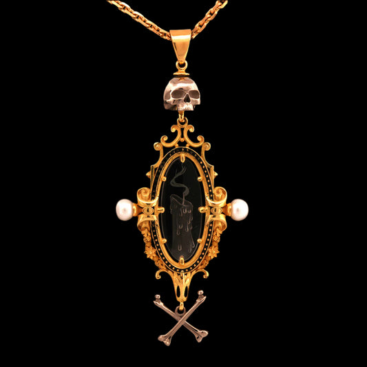 An 18ct yellow gold pendant necklace with a carved intaglio quartz crystal of a snuffed out candle, topped and tailed with a white gold skull and crossbones, suspended from a yellow gold chain.