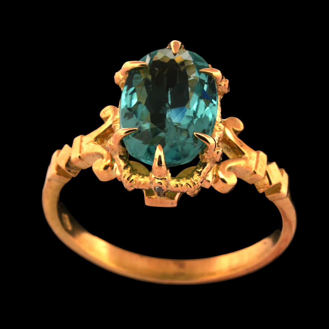 Gold ring with a pale blue tourmaline gemstone on a black background