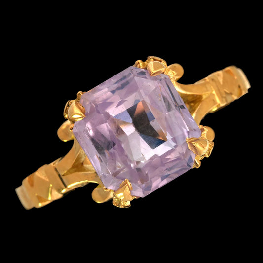Gold ring with a pale sapphire gemstone on a black background