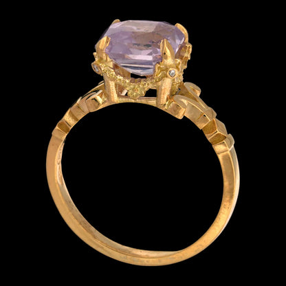 Gold ring with a lilac sapphire gemstone on a black background