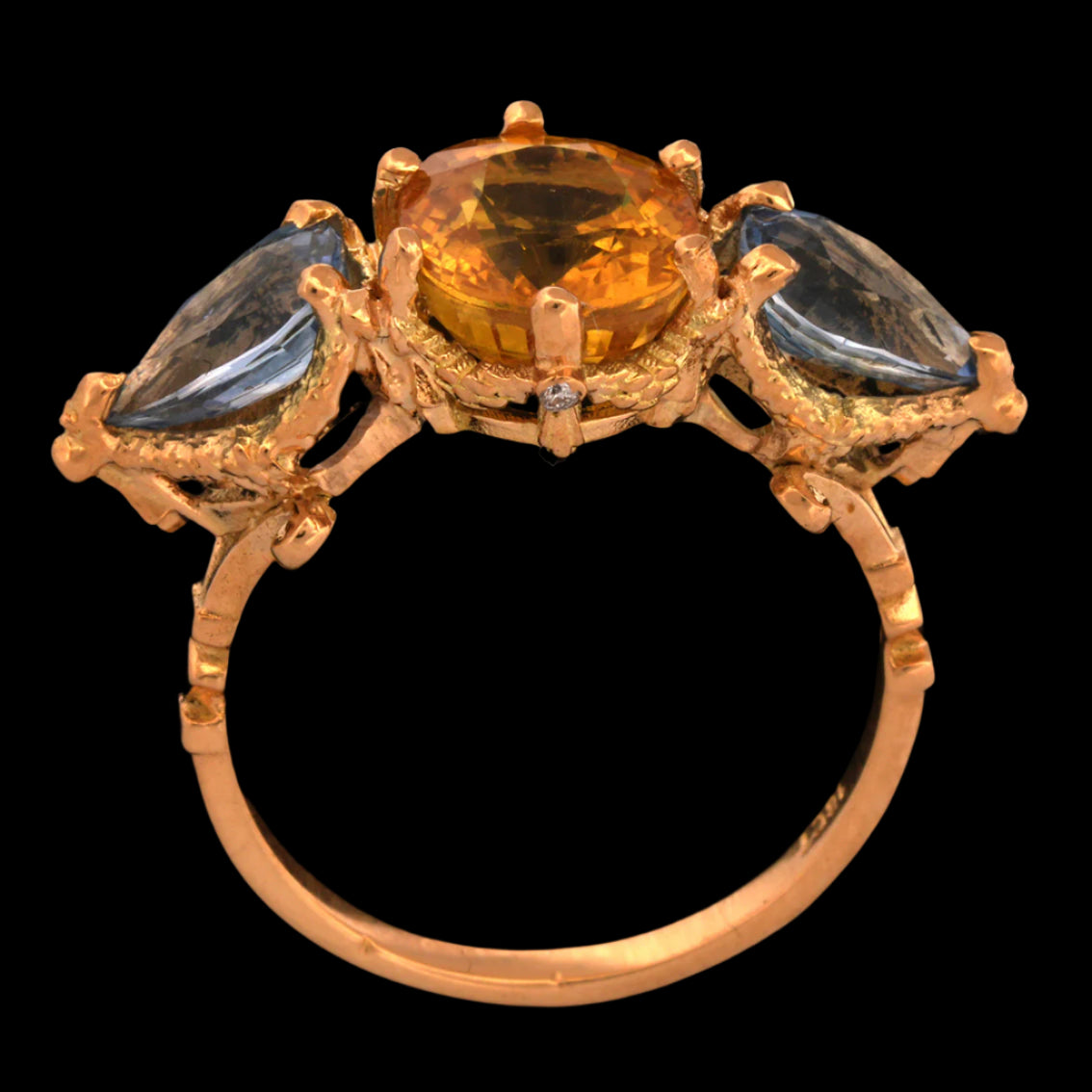 Gold ring with central yellow sapphire gemstone and two smaller blue sapphires on a black background.