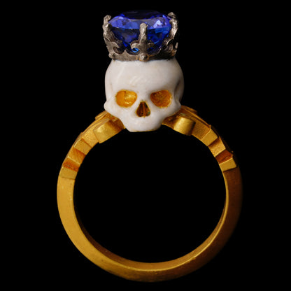 A 22kt yellow gold ring with a baroque style enamelled skull on top, crowned with a platinum crown and a tanzanite gemstone.