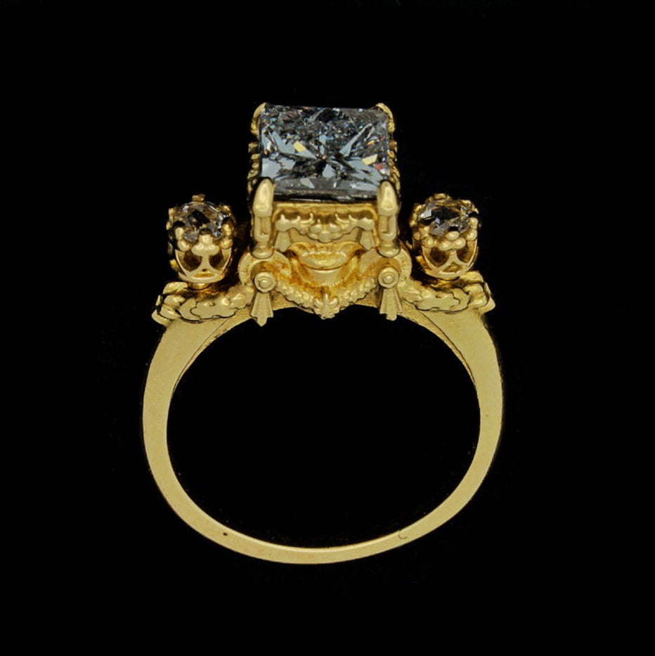 A gold ring featuring a princess cut diamond centerpiece with two rose cut diamonds on either side, set in an 18ct yellow gold band.