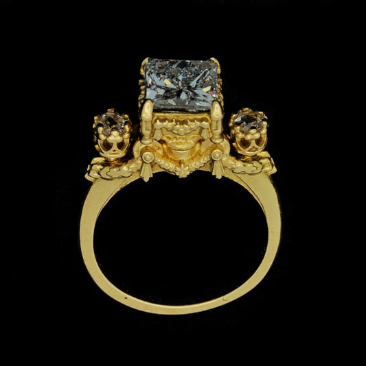 A gold ring featuring a princess cut diamond centerpiece with two rose cut diamonds on either side, set in an 18ct yellow gold band.