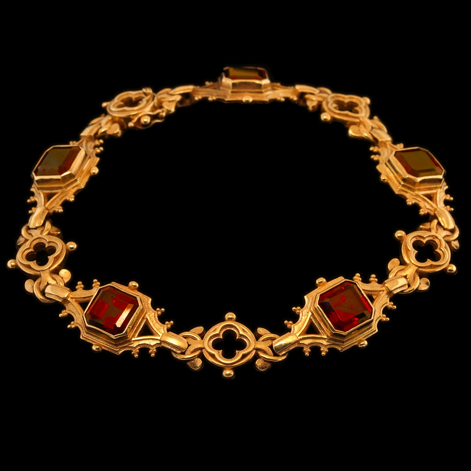 A 9 carat gold bracelet featuring a series of deep red garnets in gothic ornate settings, linked together.
