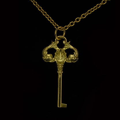 An 9ct yellow gold necklace in the shape of a key with two fish, hanging from a yellow gold curb link chain.